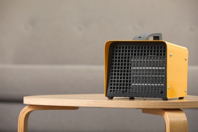 Photo of Modern electric fan heater on coffee table in cozy room. Space for text