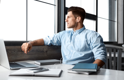 Photo of Man listening to audiobook at table in cafe