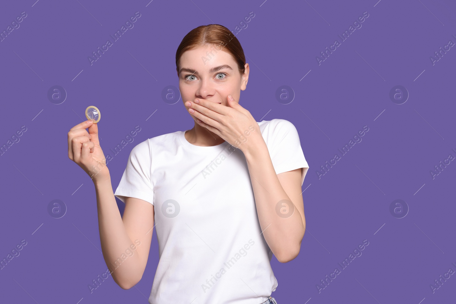 Photo of Woman holding condom on purple background. Safe sex