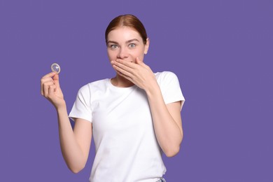 Woman holding condom on purple background. Safe sex