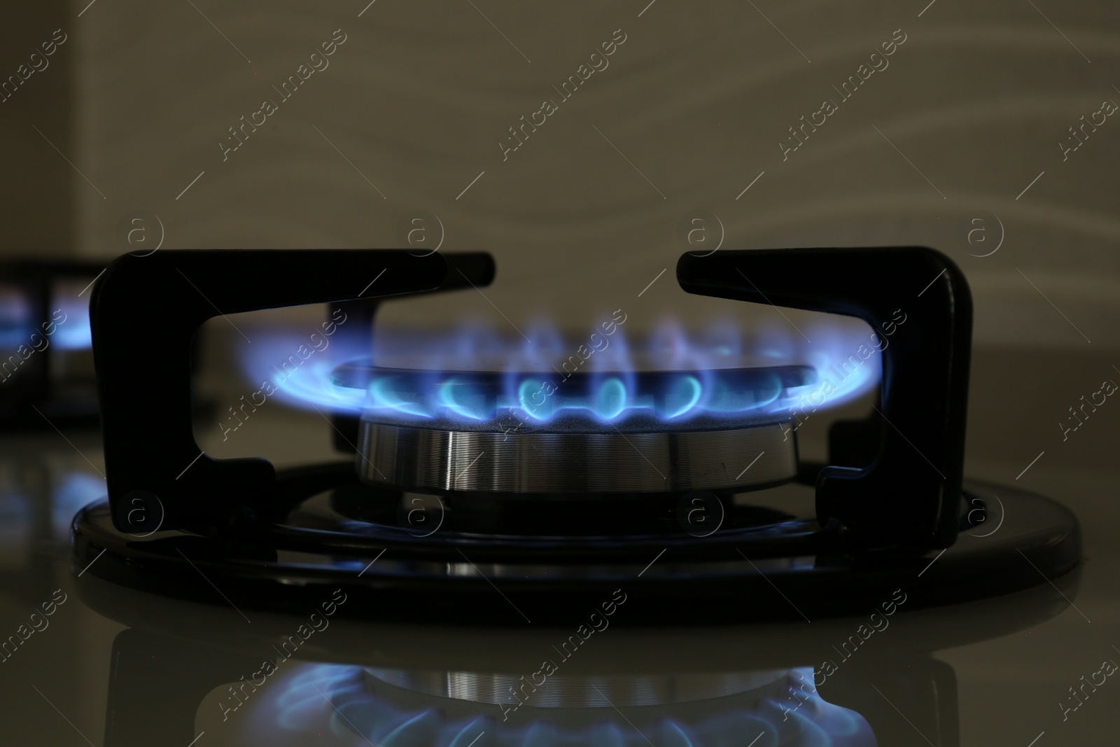 Photo of Gas burner of modern stove with burning blue flame, closeup