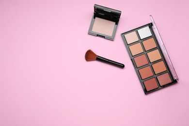 Contouring palettes and brush on pink background, flat lay with space for text. Professional cosmetic product