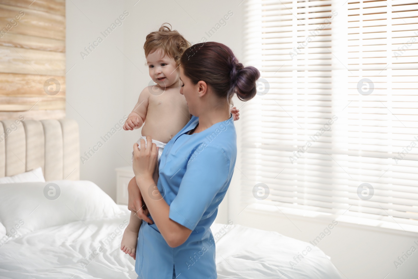 Photo of Female orthopedist with cute little baby indoors