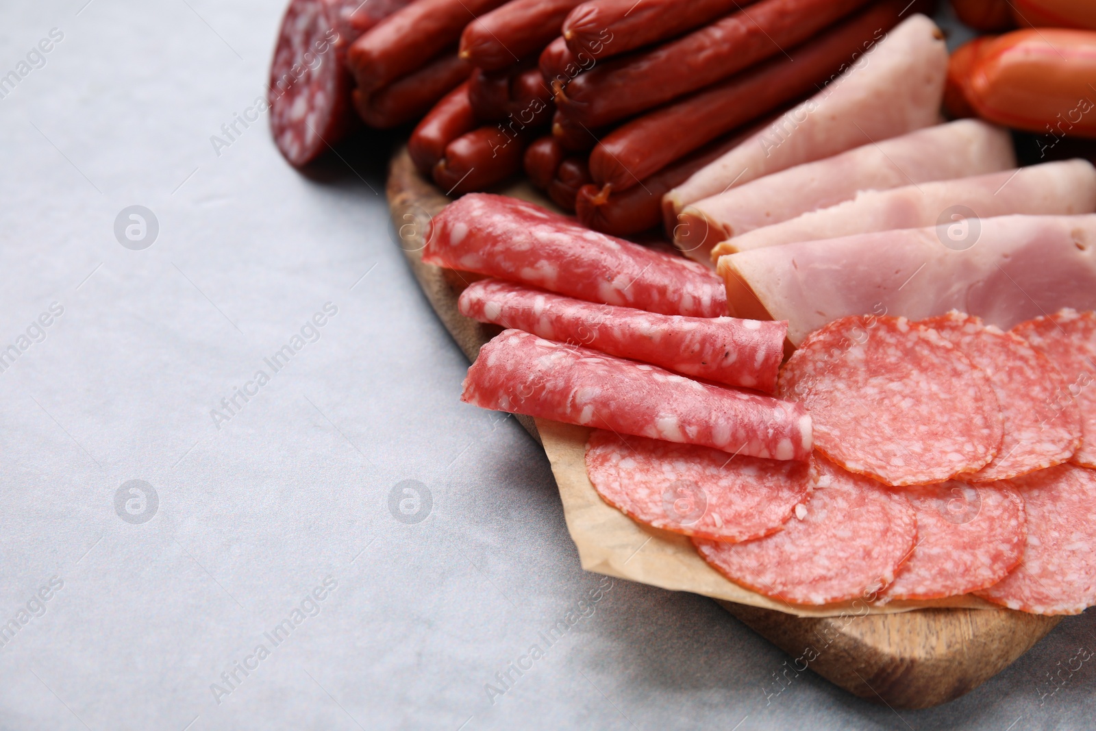 Photo of Different types of sausages on light grey table, closeup. Space for text