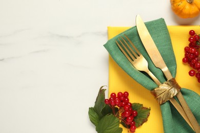 Photo of Autumn table setting. Cutlery, napkins, viburnum berries and pumpkin on white marble background, flat lay with space for text