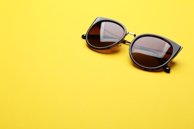 Stylish sunglasses on yellow background, space for text. Fashionable accessory