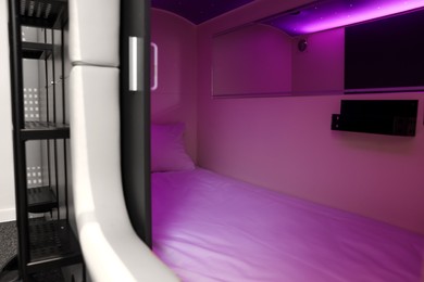 Photo of Capsule with bed and purple light in modern pod hostel