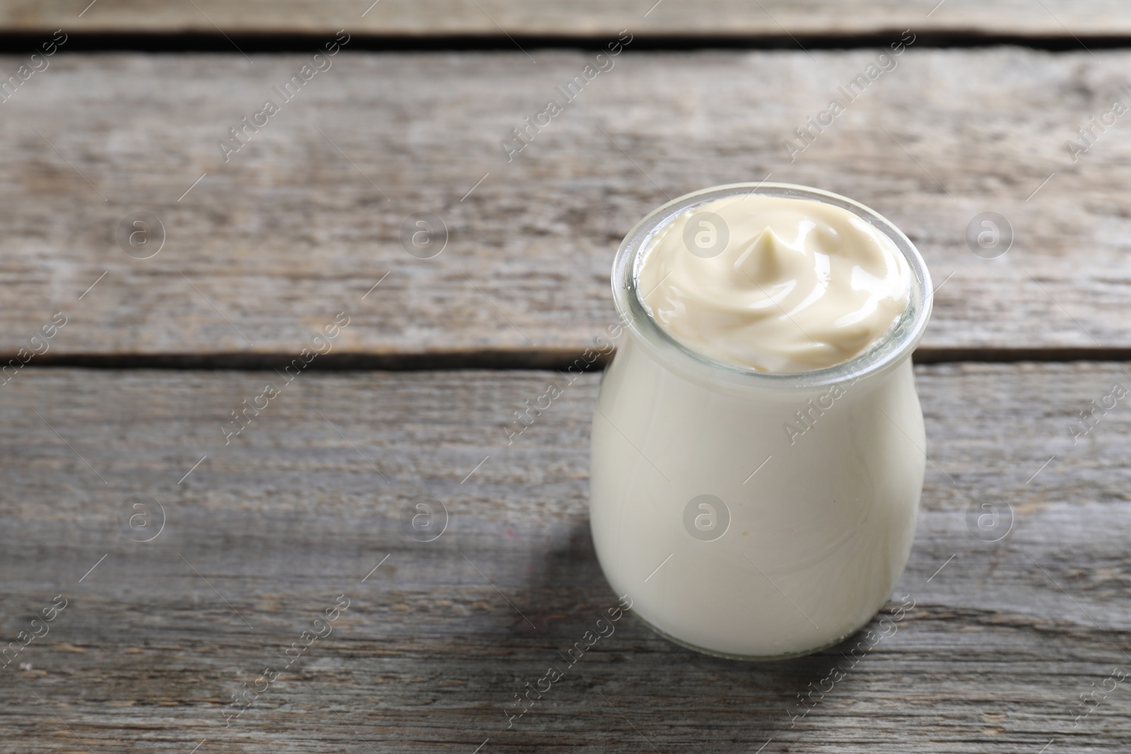 Photo of Fresh mayonnaise sauce in glass jar on wooden table, space for text