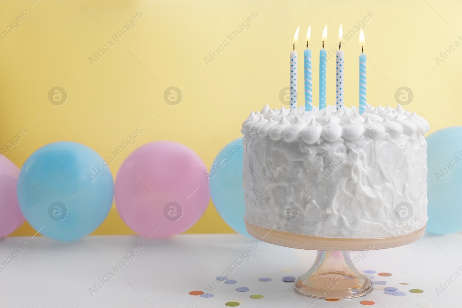 Photo of Delicious cake with burning candles and decorations on white table. Space for text