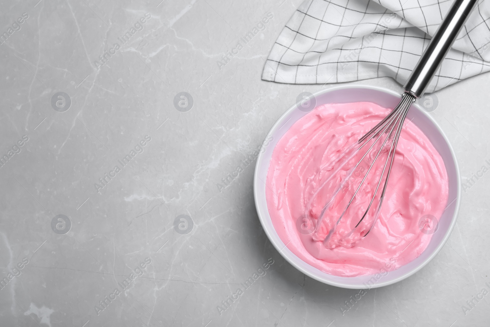 Photo of Pink cream with balloon whisk on light grey table, flat lay. Space for text