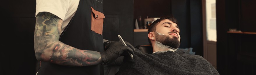 Image of Professional hairdresser working with bearded client in barbershop. Banner design