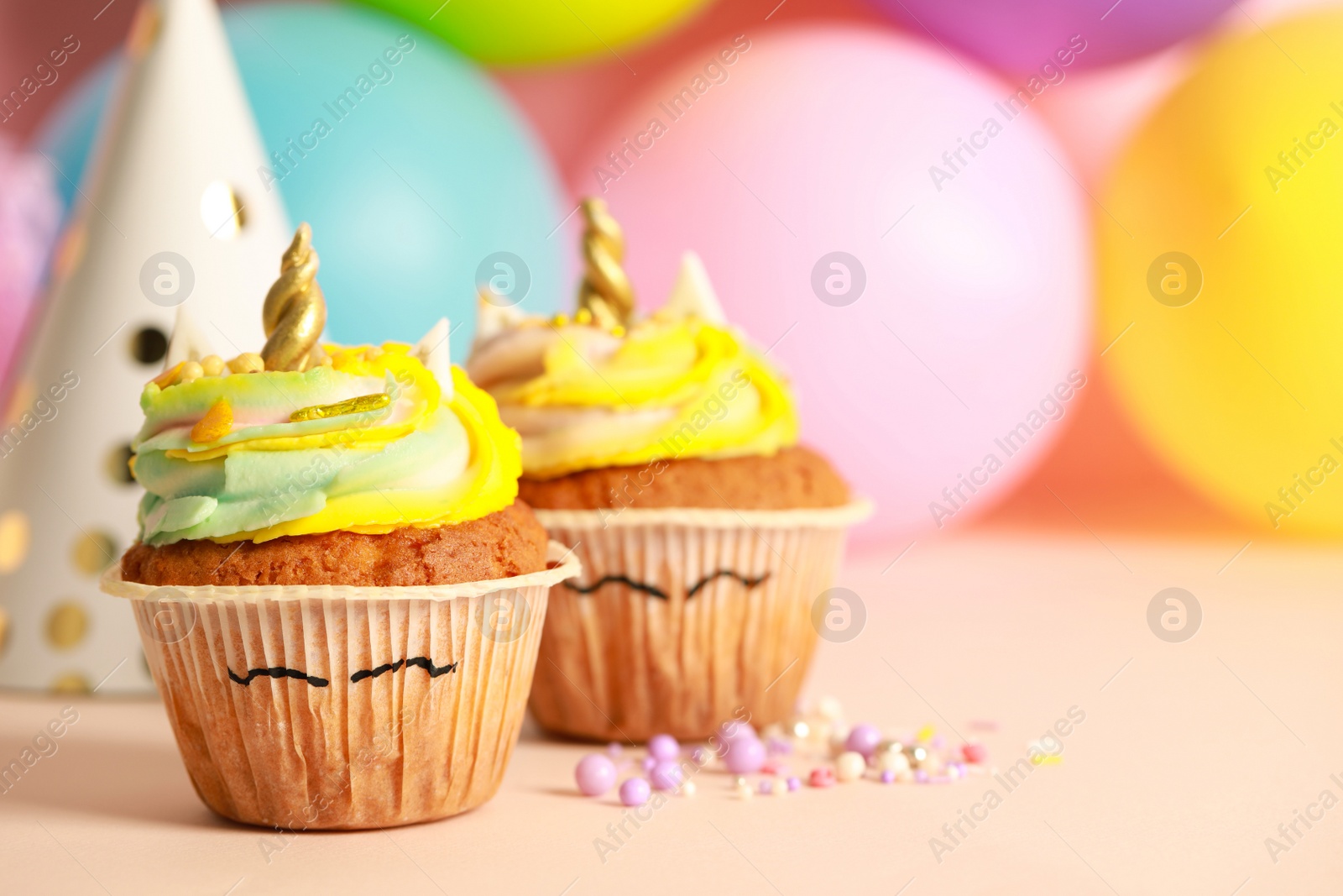 Photo of Cute sweet unicorn cupcakes on beige table, space for text