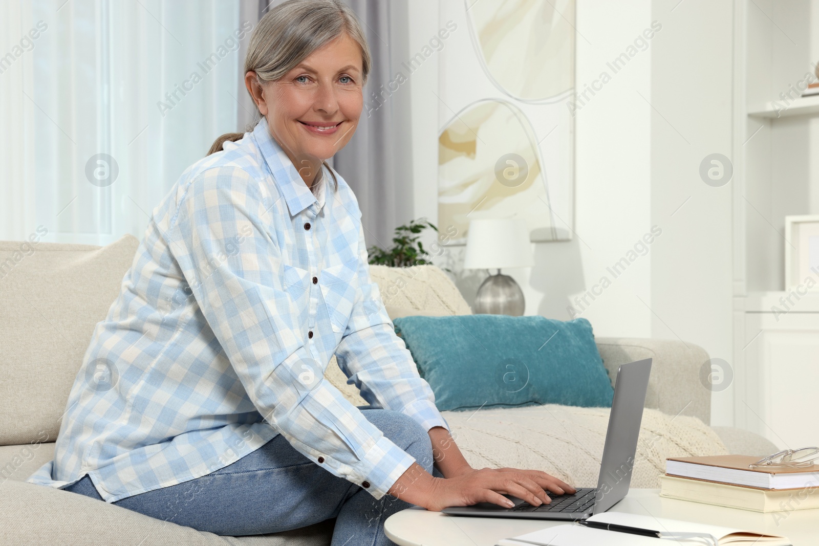 Photo of Beautiful senior woman using laptop at home, space for text