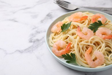 Tasty spaghetti with shrimps and parsley on white marble table, closeup. Space for text