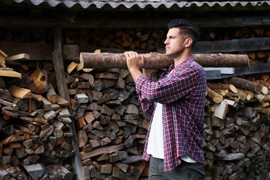 Photo of Man with log near wood pile outdoors