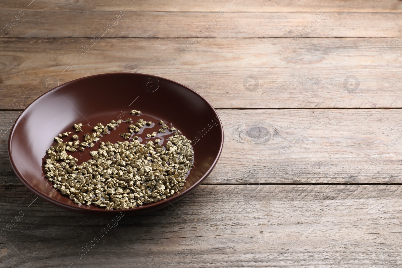 Photo of Plate of gold nuggets on wooden table. Space for text