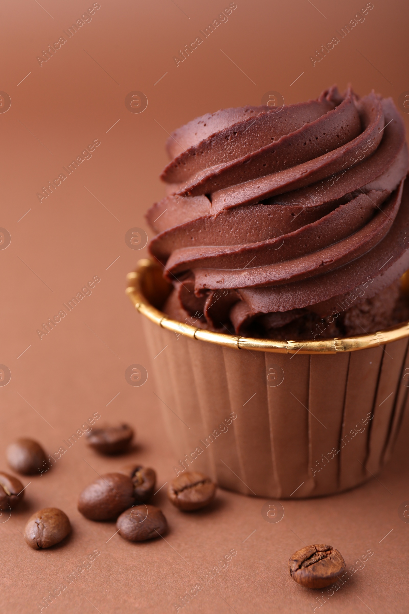 Photo of Delicious chocolate cupcake and coffee beans on brown background, closeup