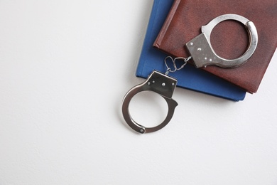 Photo of Flat lay composition with books and handcuffs on white background, space for text. Criminal law