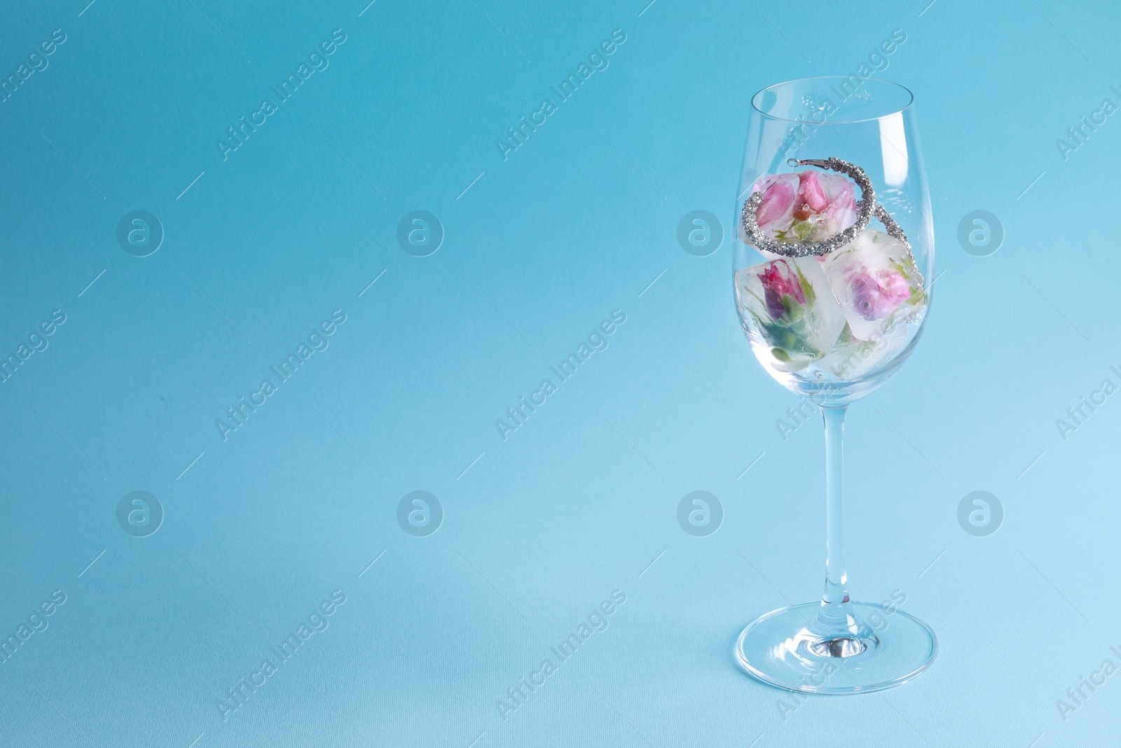 Photo of Elegant jewelry. Stylish presentation with luxury earrings and frozen roses in glass on light blue background. Space for text