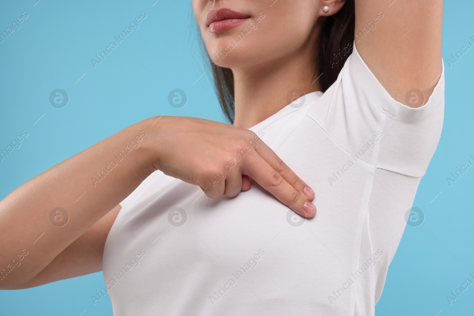 Photo of Woman doing breast self-examination on light blue background, closeup