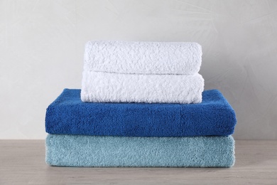 Photo of Stacked fresh soft towels on grey wooden table