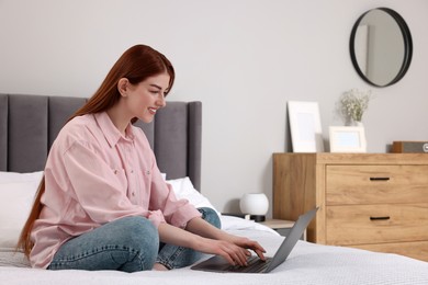 Photo of Happy woman with laptop on bed in bedroom