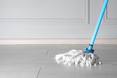 Cleaning of parquet floor with mop indoors, space for text
