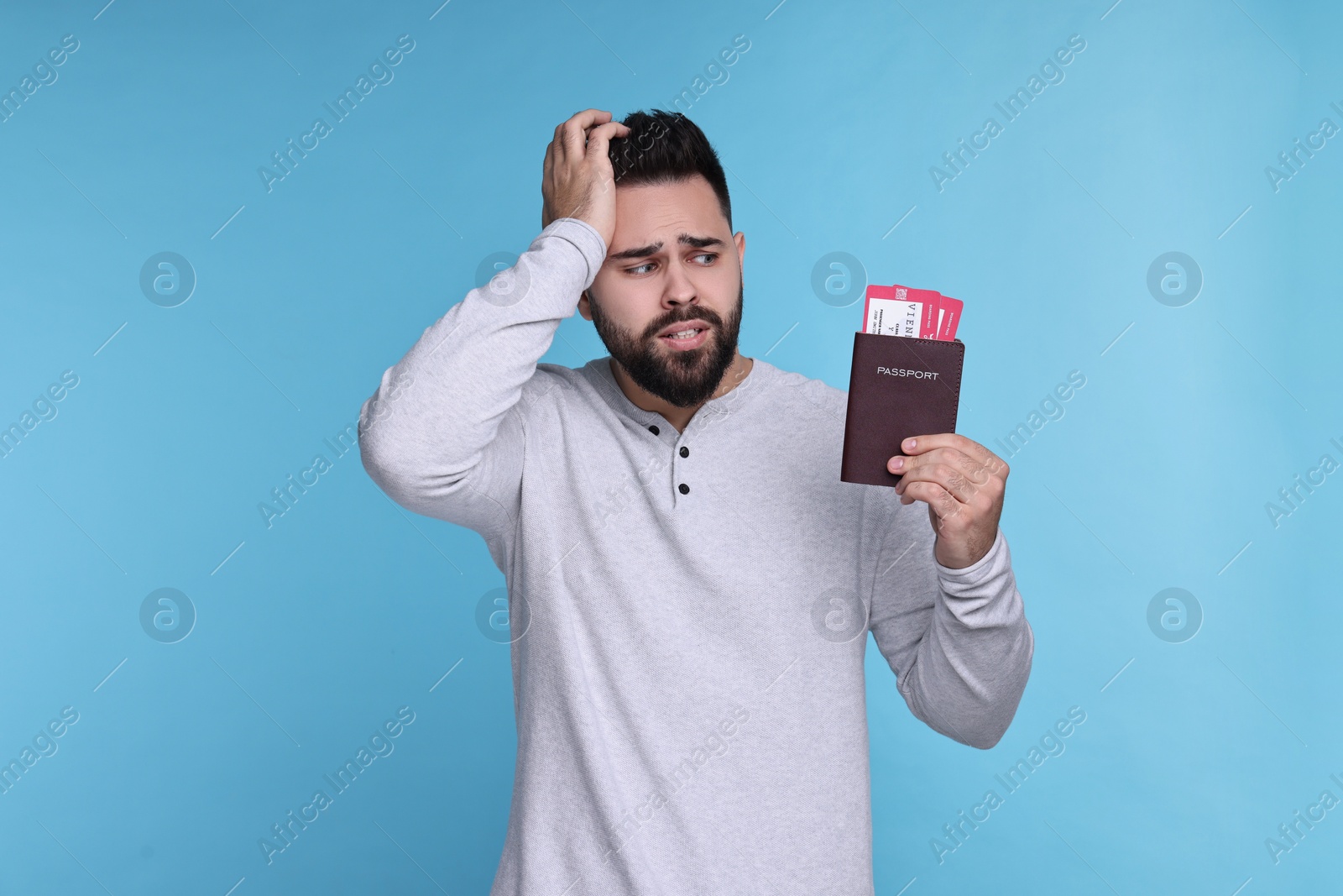 Photo of Emotional man with passport and tickets on light blue background