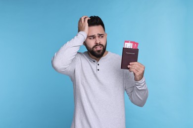 Emotional man with passport and tickets on light blue background