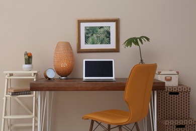 Stylish workplace with laptop on table in office