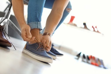 Young man trying on shoes in store