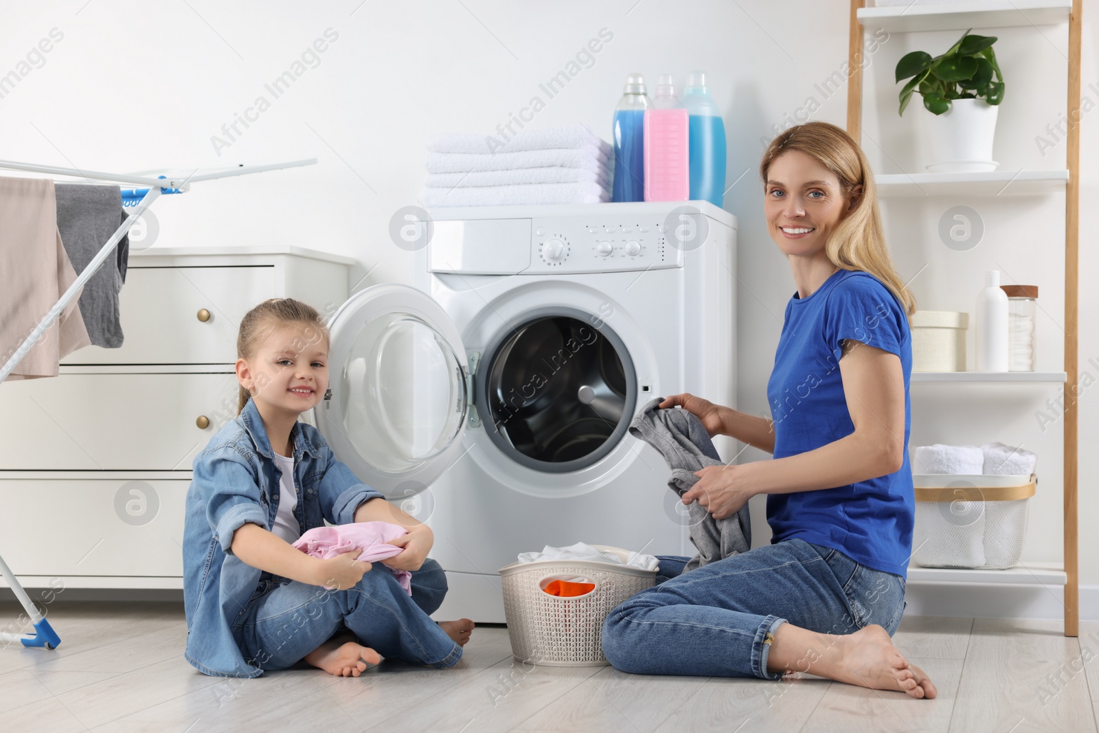 Photo of Mother and daughter taking out dirty clothes from basket in bathroom