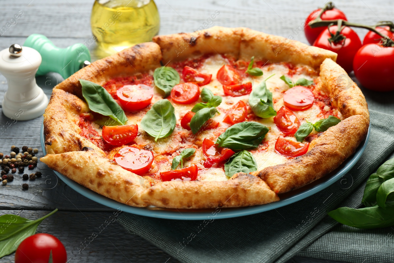 Photo of Delicious Margherita pizza and ingredients on gray wooden table, closeup
