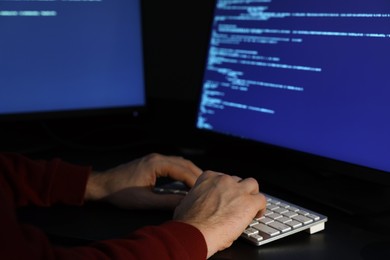 Photo of Hacker working with computers in dark room, closeup. Cyber attack