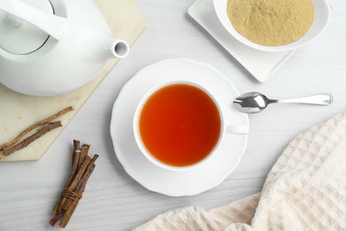 Photo of Aromatic licorice tea in cup served on white wooden table, flat lay