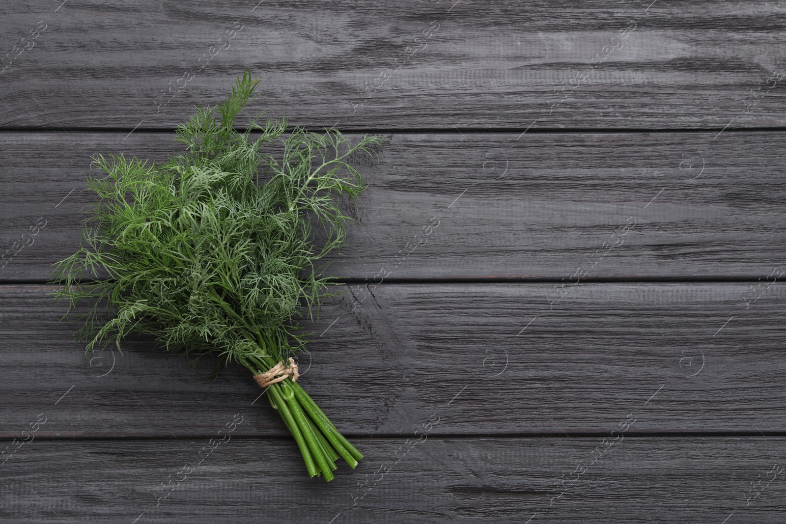 Photo of Bunch of fresh dill on wooden table, top view. Space for text