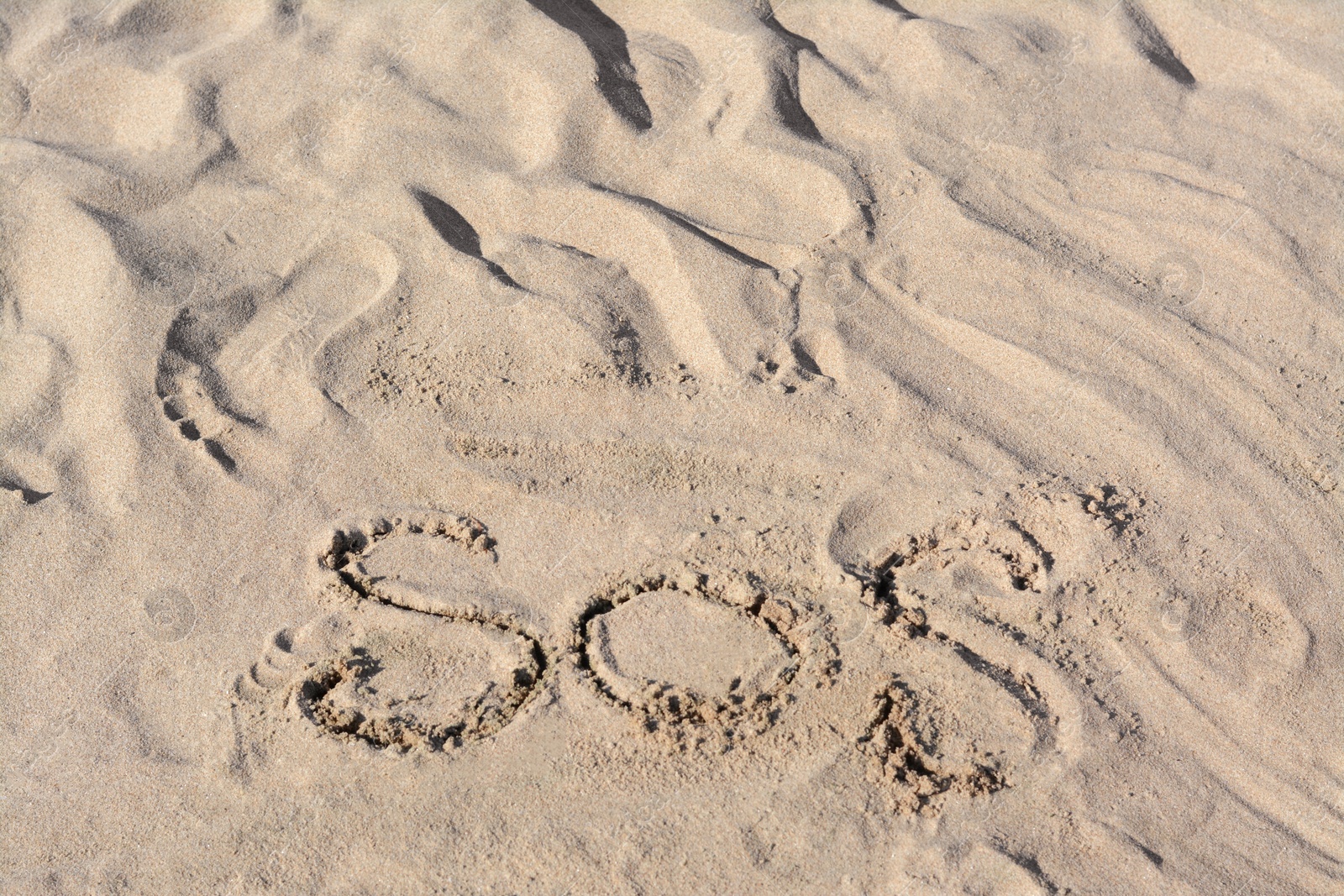 Photo of SOS message written on sandy beach outdoors
