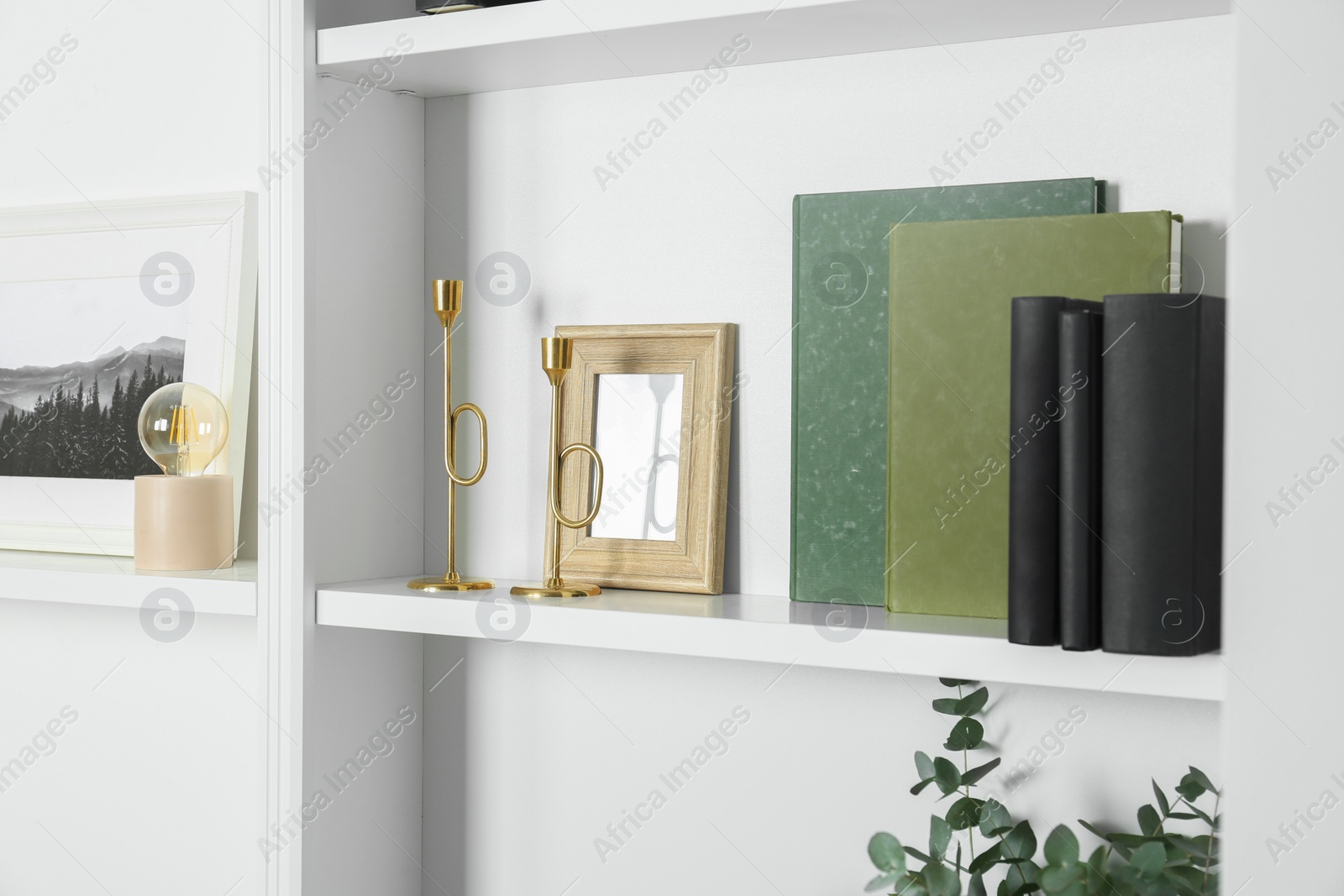 Photo of White shelves with books and different decor indoors. Interior design