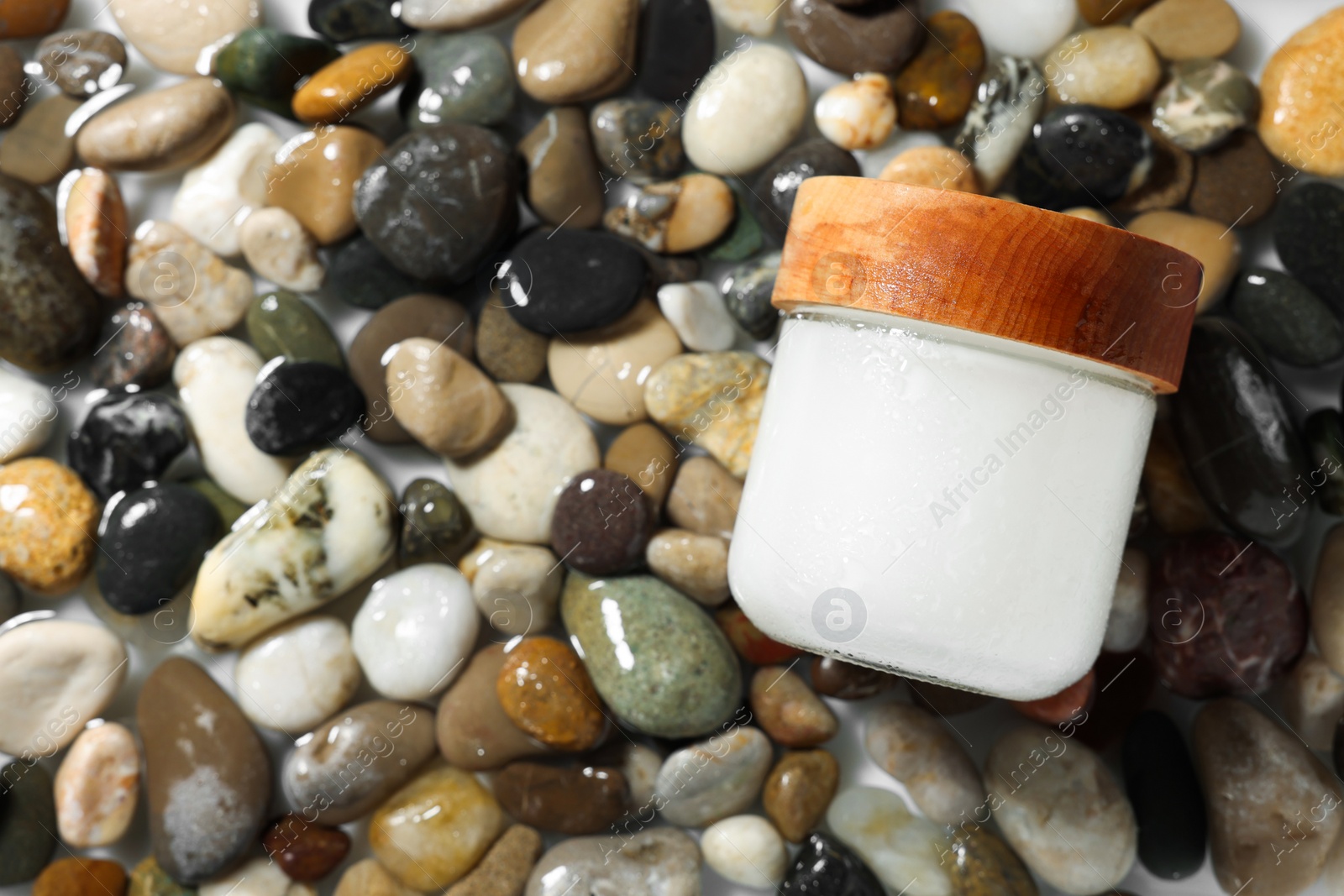 Photo of Jar of cosmetic product on wet stones, top view. Space for text