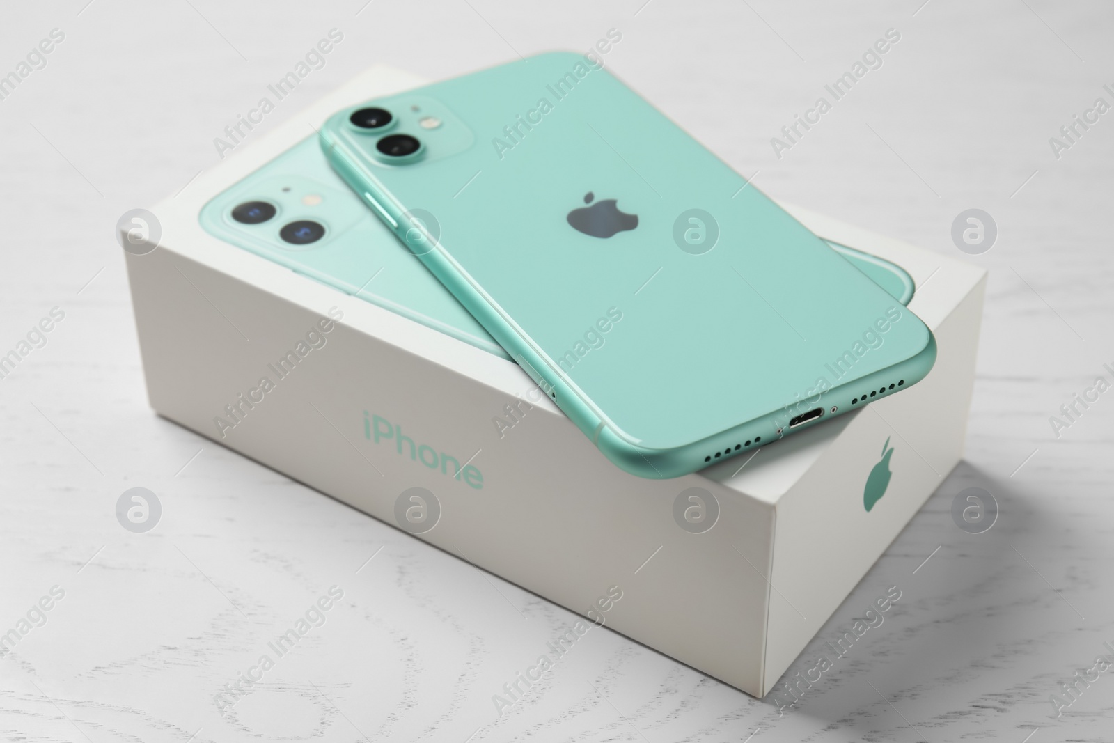 Photo of MYKOLAIV, UKRAINE - JULY 10, 2020: New modern Iphone 11 Green and original box on white wooden table