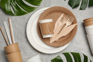 Photo of Flat lay composition with disposable tableware and monstera leaves on light grey background