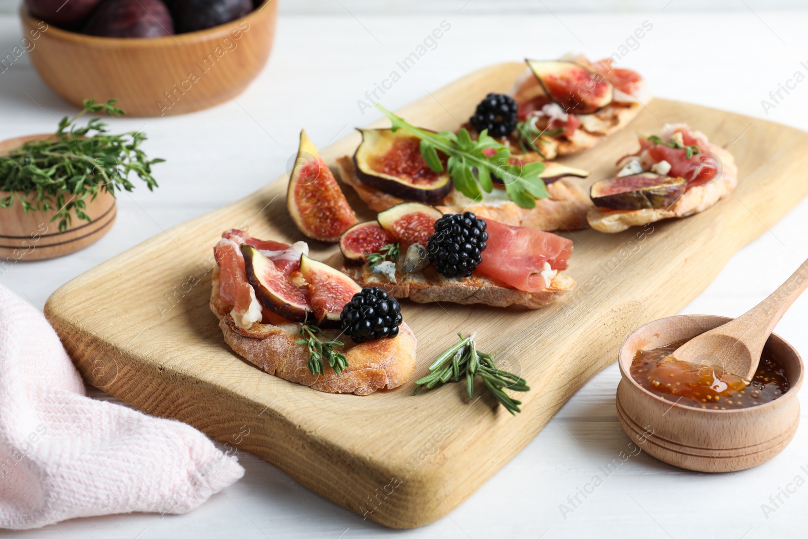 Photo of Sandwiches with ripe figs and prosciutto served on white wooden table