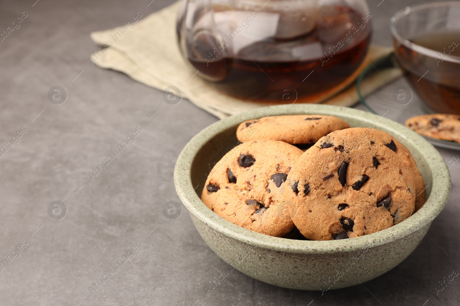 Photo of Delicious chocolate chip cookies and tea on grey table. Space for text