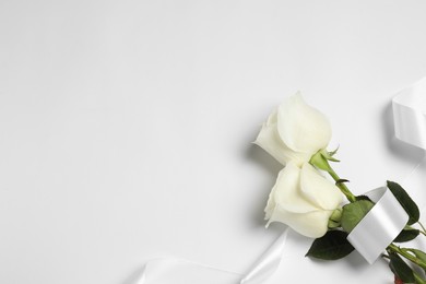 Beautiful roses and ribbon on white background, flat lay with space for text. Funeral symbols