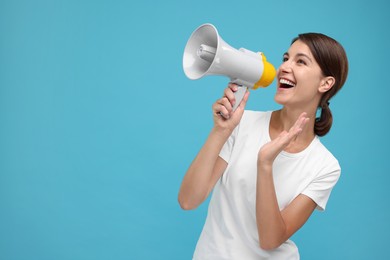 Photo of Special promotion. Young woman shouting in megaphone on light blue background, space for text