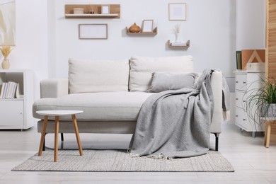 Photo of Grey plaid on comfortable sofa in living room