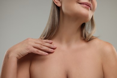 Mature woman with healthy skin on grey background, closeup