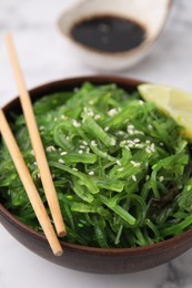 Tasty seaweed salad in bowl served on white table, closeup