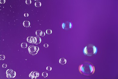 Photo of Beautiful transparent soap bubbles on purple background