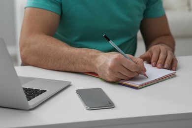 Photo of Online test. Man studying at desk indoors, closeup